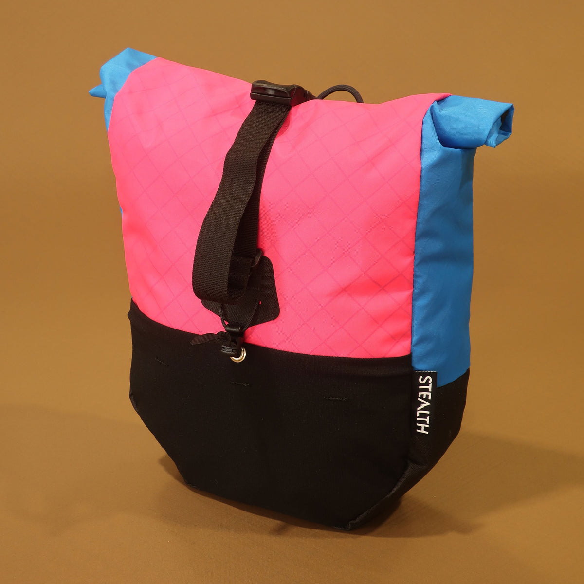 Pink, blue and black mountain bike pannier with a roll top closure, adjustable attachment straps and spacious stretch front pocket.