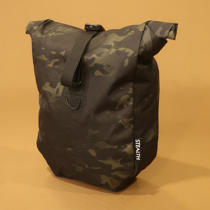 Multicam Black mountain pannier with a roll top and attachment straps for mountain biking and bikepacking