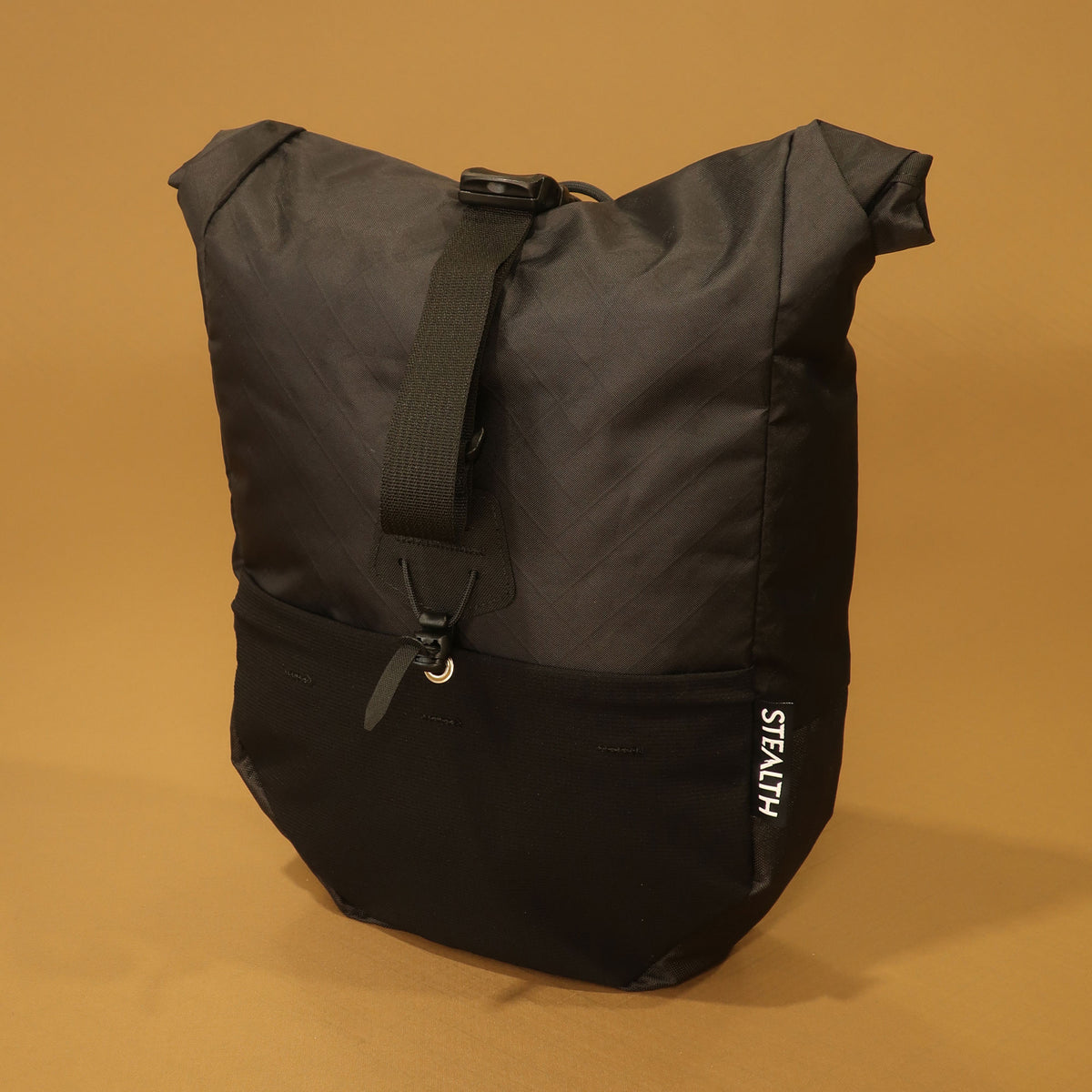 Black mountain pannier with a roll top closure, front stretch pocket, and adjustable attachment strap for bikepacking and mountain biking