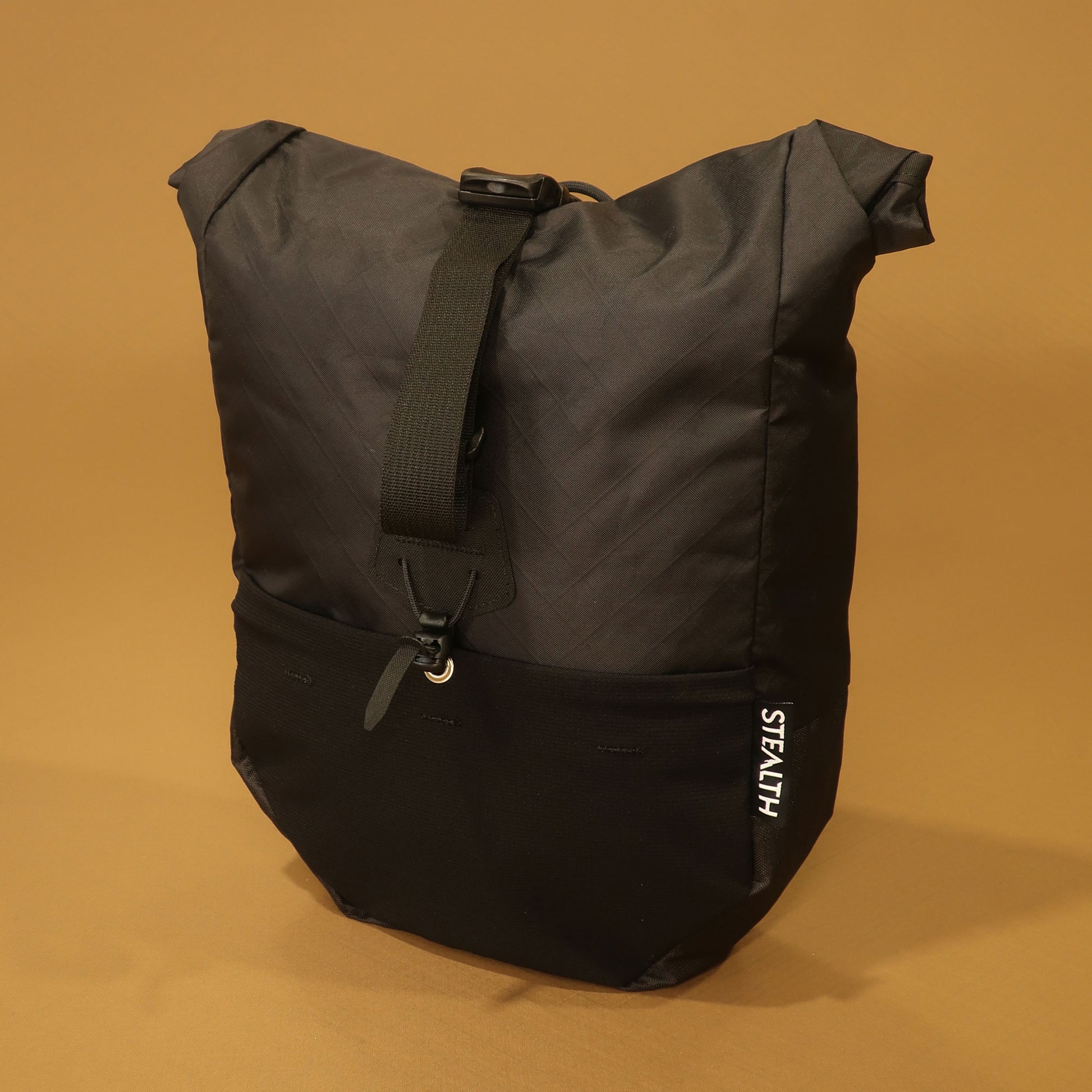 Black mountain pannier with a roll top closure, front stretch pocket, and adjustable attachment strap for bikepacking and mountain biking