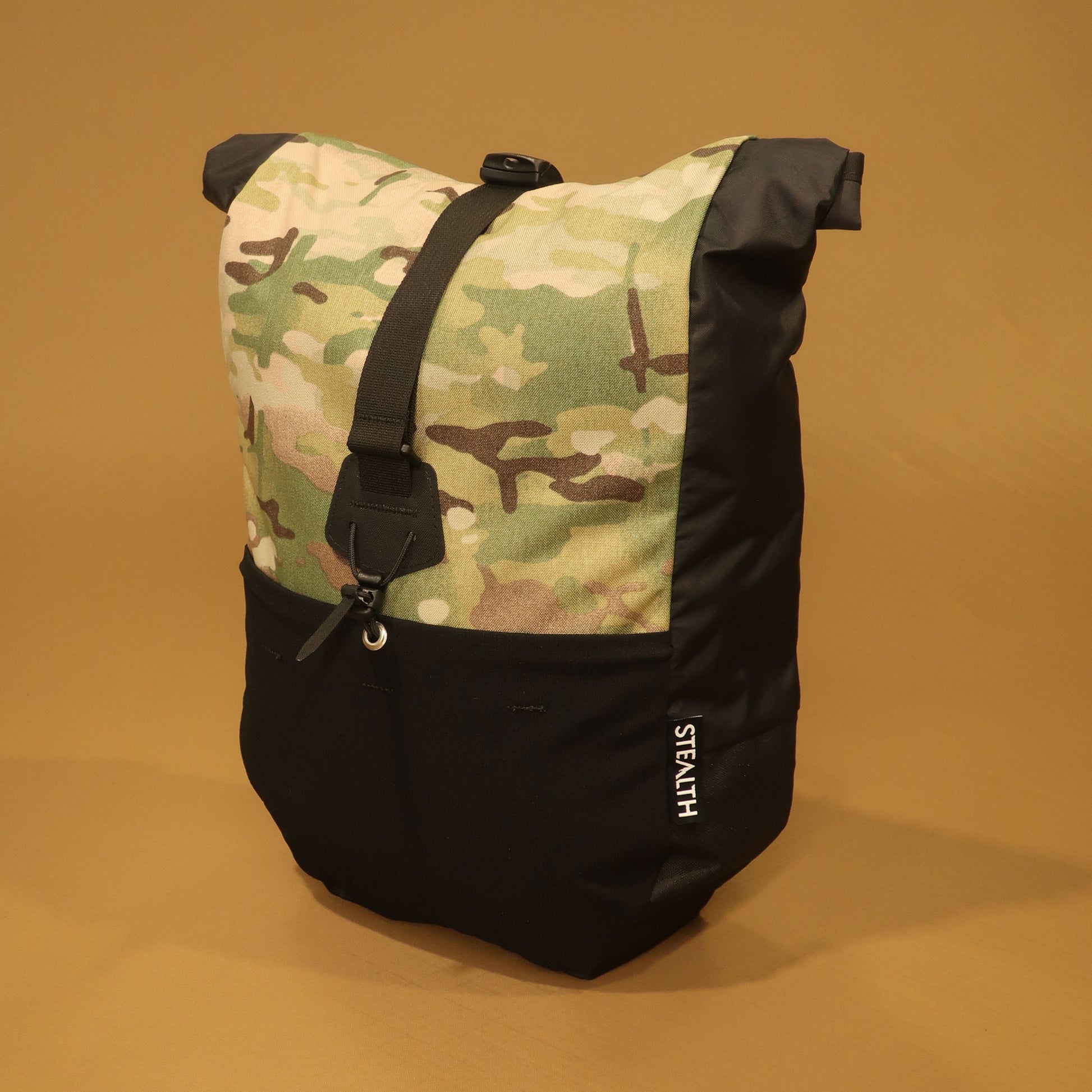 Black and Multicam Mountain Pannier made from recycled Ecopak fabric, with a roll top closure and front compression strap for mountain biking and bikepacking.
