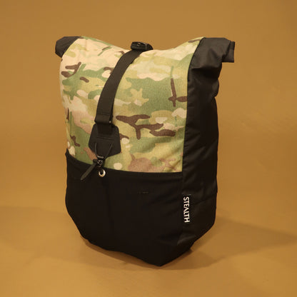 Black and Multicam Mountain Pannier made from recycled Ecopak fabric, with a roll top closure and front compression strap for mountain biking and bikepacking.