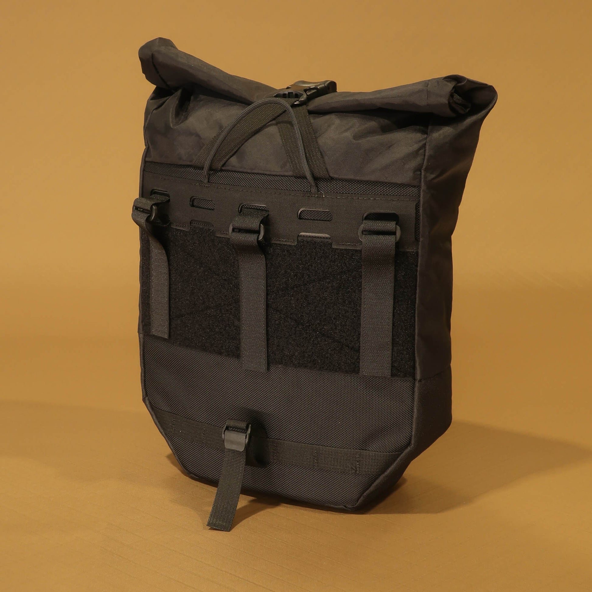 Rear view of black 10L roll-top bicycle pannier showing full rack attachment panel with carry handle