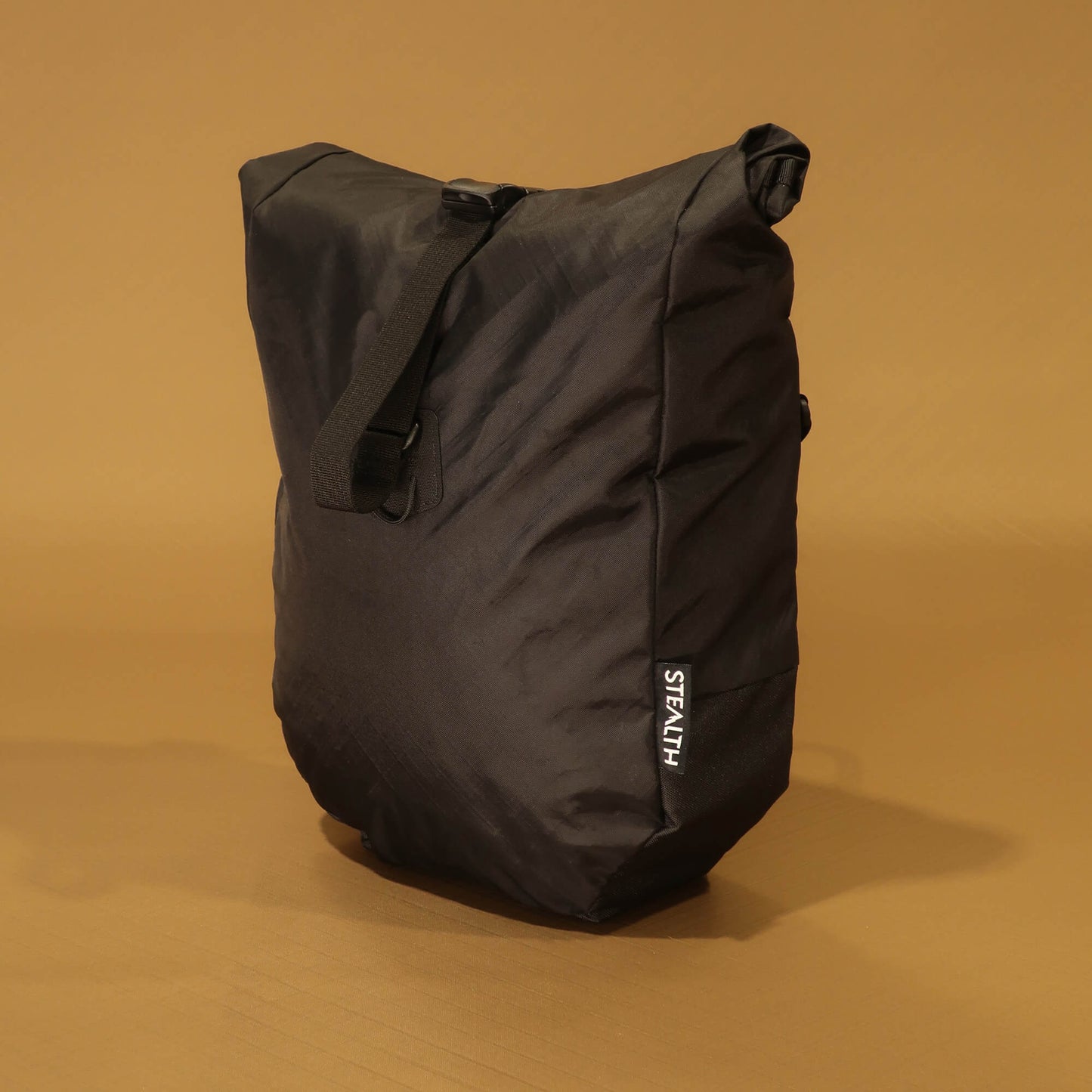 Front view of black 10L roll-top bicycle pannier with carry handle and roll-top buckle closure