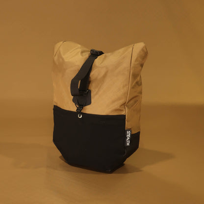Front view of 10L roll-top bicycle pannier in coyote tan with black base, showing roll-top closure strap and Stealth logo label