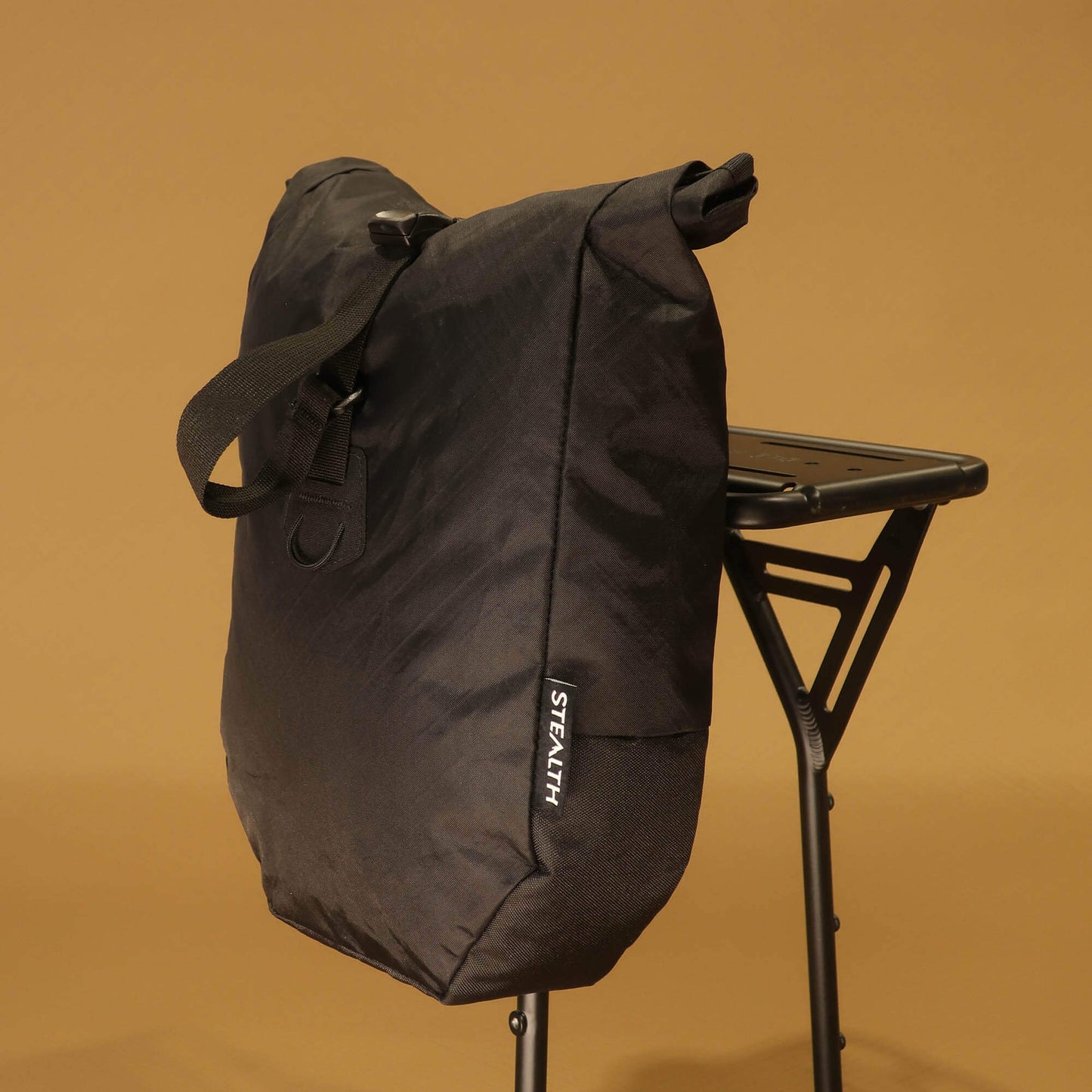 Front view of black 8L roll-top bicycle pannier with carry handle and roll-top closure buckle