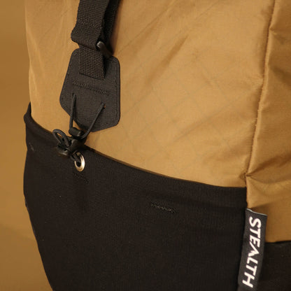 Close-up detail of the 8L Coyote pannier showing the side attachment hook, eyelet, and the two-tone coyote tan and black fabric join with Stealth branding label