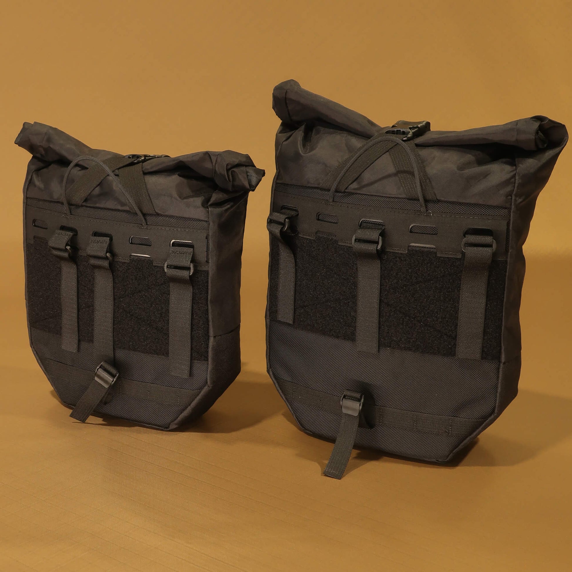 8L and 10L black panniers side by side from the rear, showing size difference in the rack attachment panels