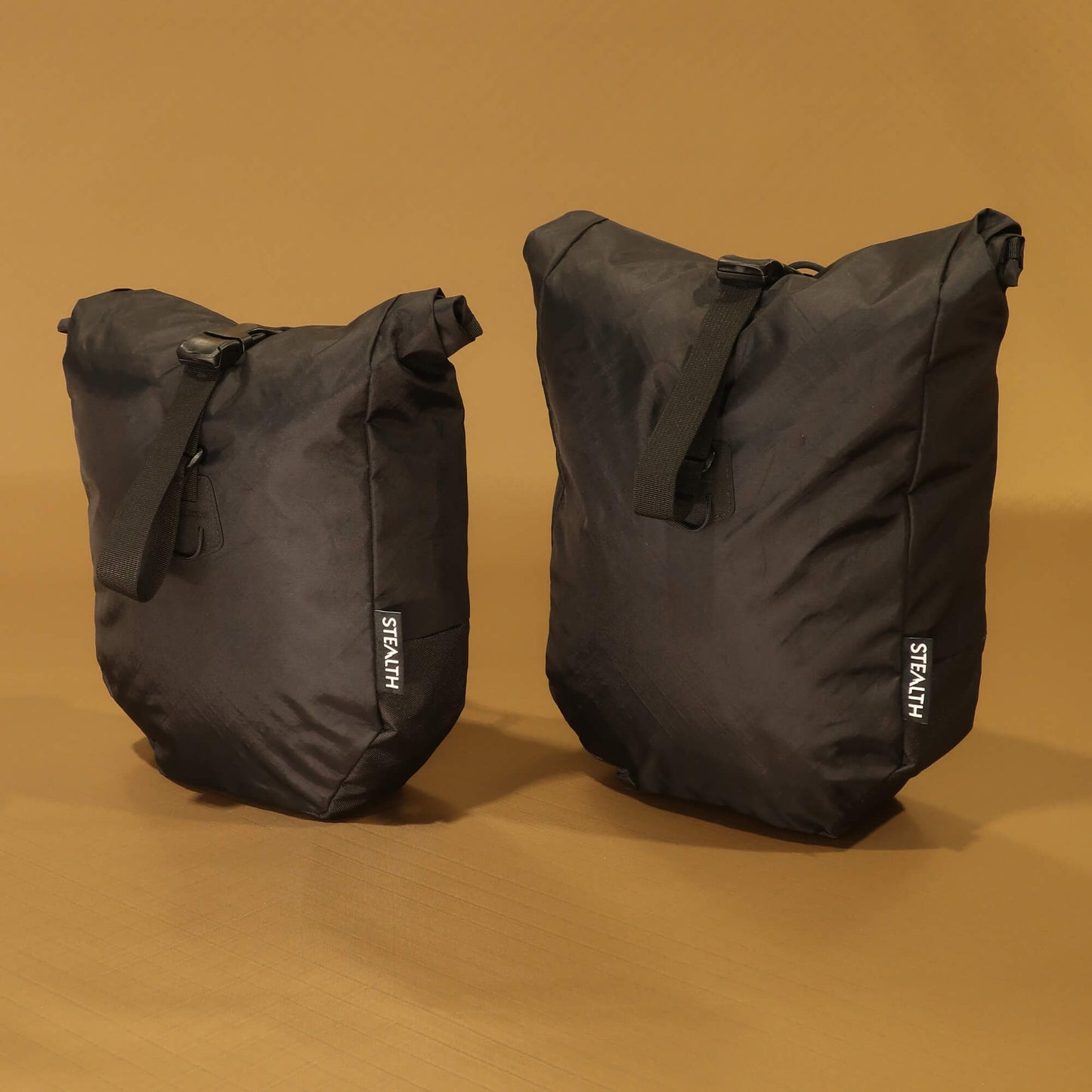 8L and 10L black panniers side by side from the front, showing the size difference when fully packed