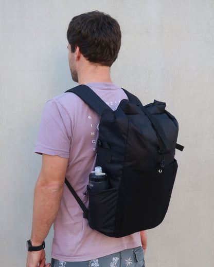 Rata 25 black commuter backpack worn showing stretch pocket and roll top closure by Stealth Wellington NZ