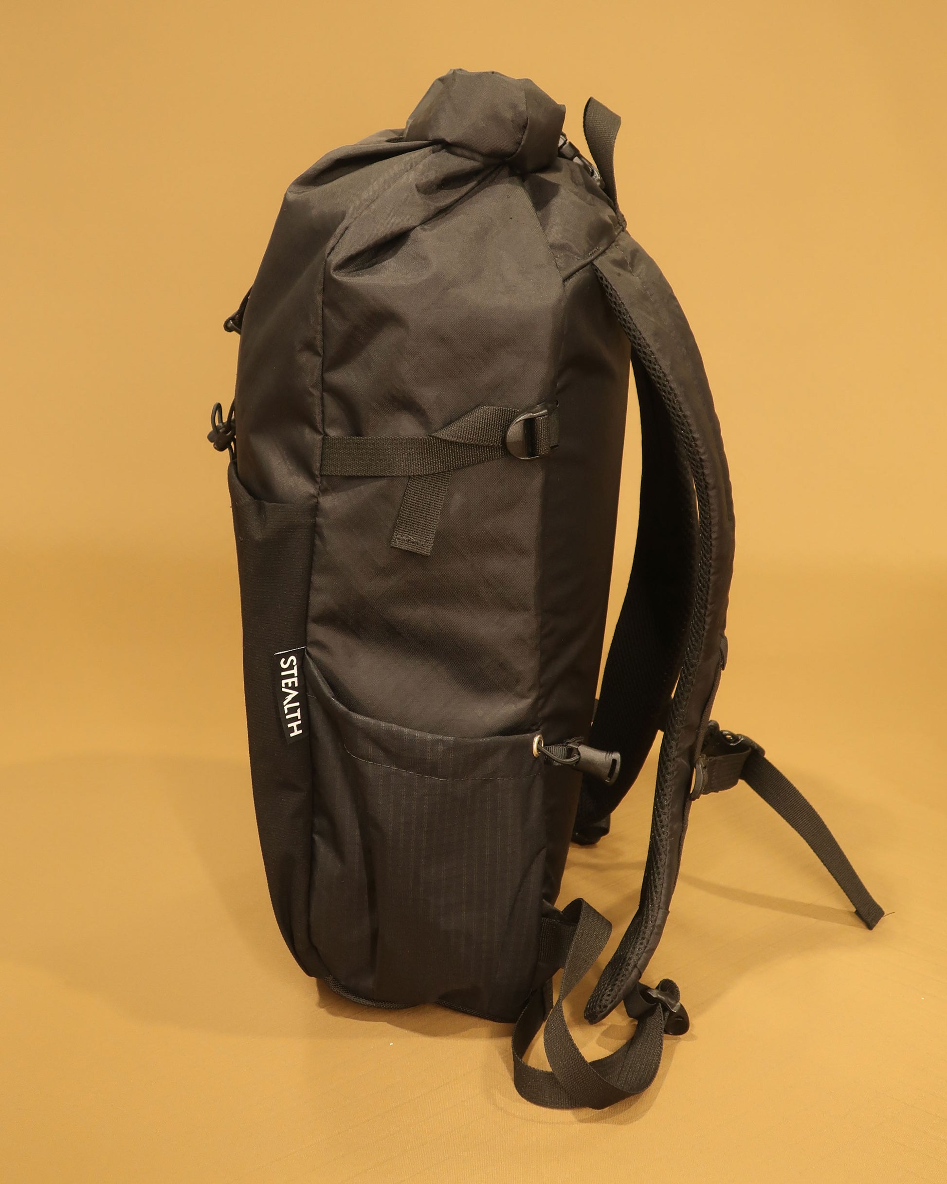 Rata 25 roll-top backpack side profile in black with ultragrid bottle pocket made by Stealth Wellington NZ
