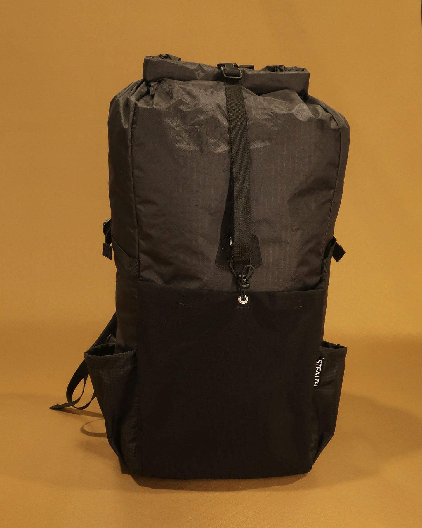 Black overnight tramping pack showing ultra-stretch front pocket with compression strap, made by Stealth Wellington NZ