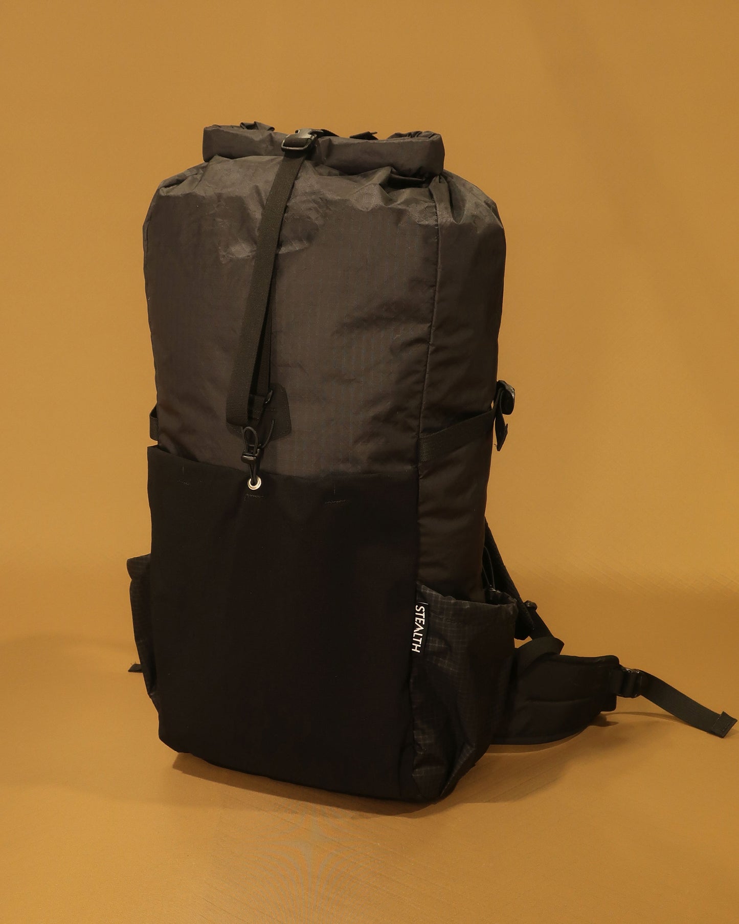 Black 40L ultralight pack showing roll-top closure and ultra-stretch front pocket, made by Stealth Wellington NZ