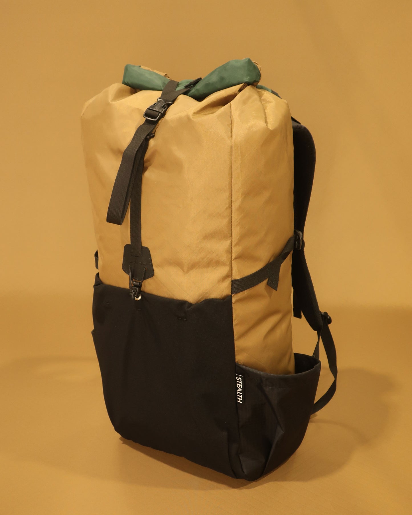 Rata 40 tramping pack in coyote tan with green accents showing roll-top closure and pocket, made by Stealth Wellington NZ