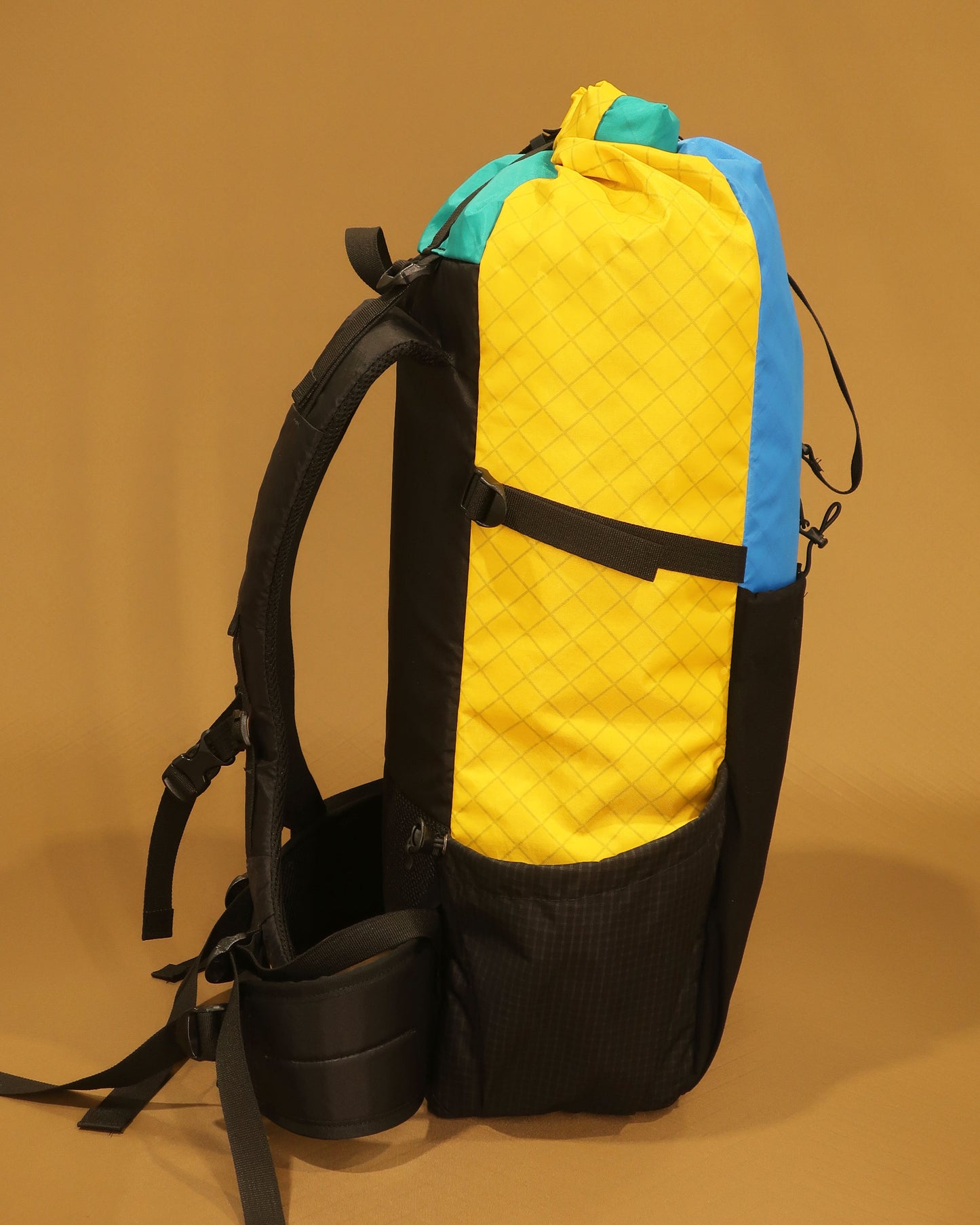 Multicolour 40L tramping pack side view with Ultragrid side pocket and single-handed closure, made by Stealth Wellington NZ