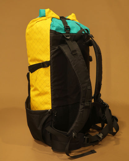 Yellow Rata 40 tramping pack side view showing compression straps and Ultragrid side pocket, made by Stealth Wellington NZ