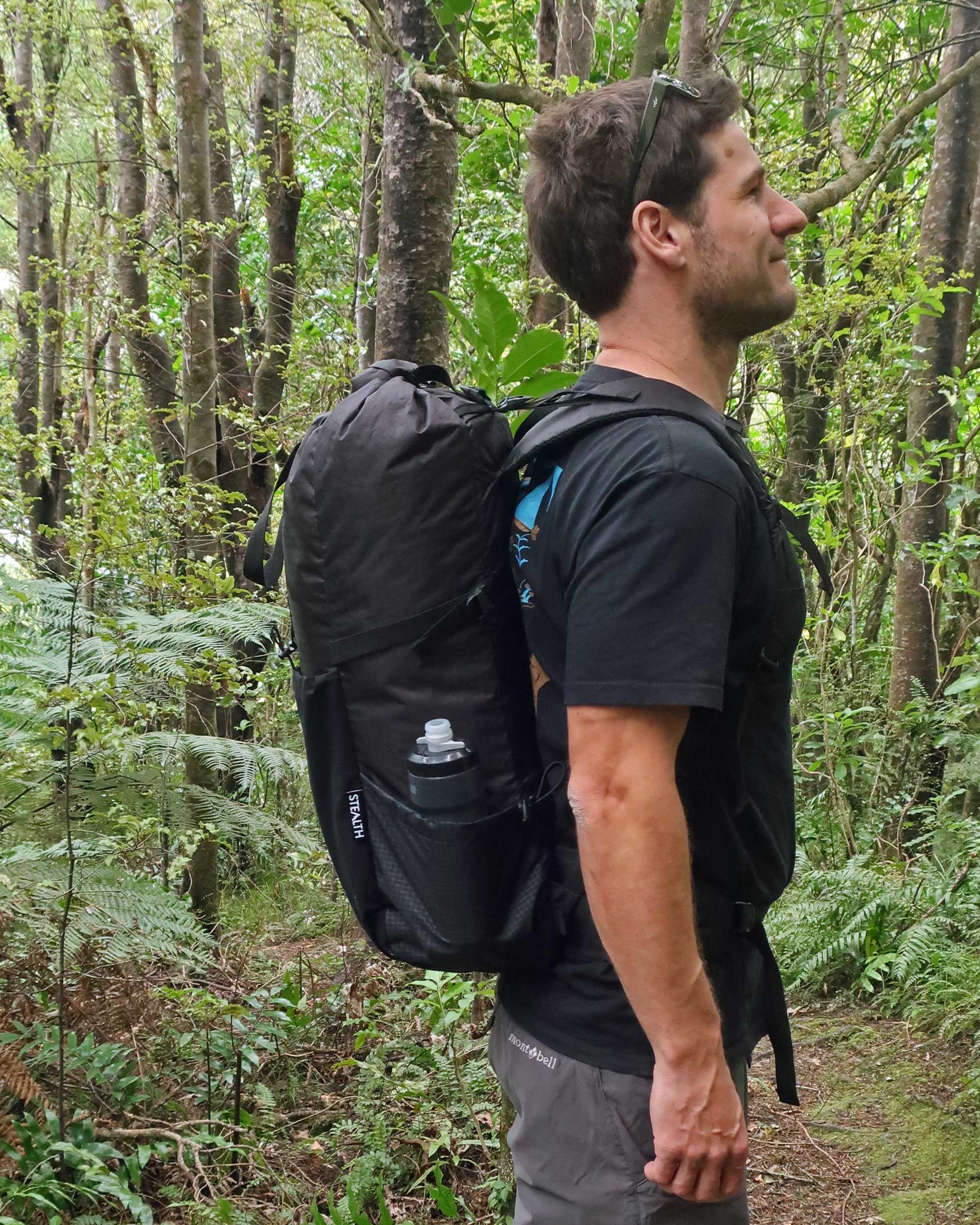 NZ made 40L tramping pack side profile on bush trail showing pack depth and Ultragrid side pocket, made by Stealth Wellington NZ