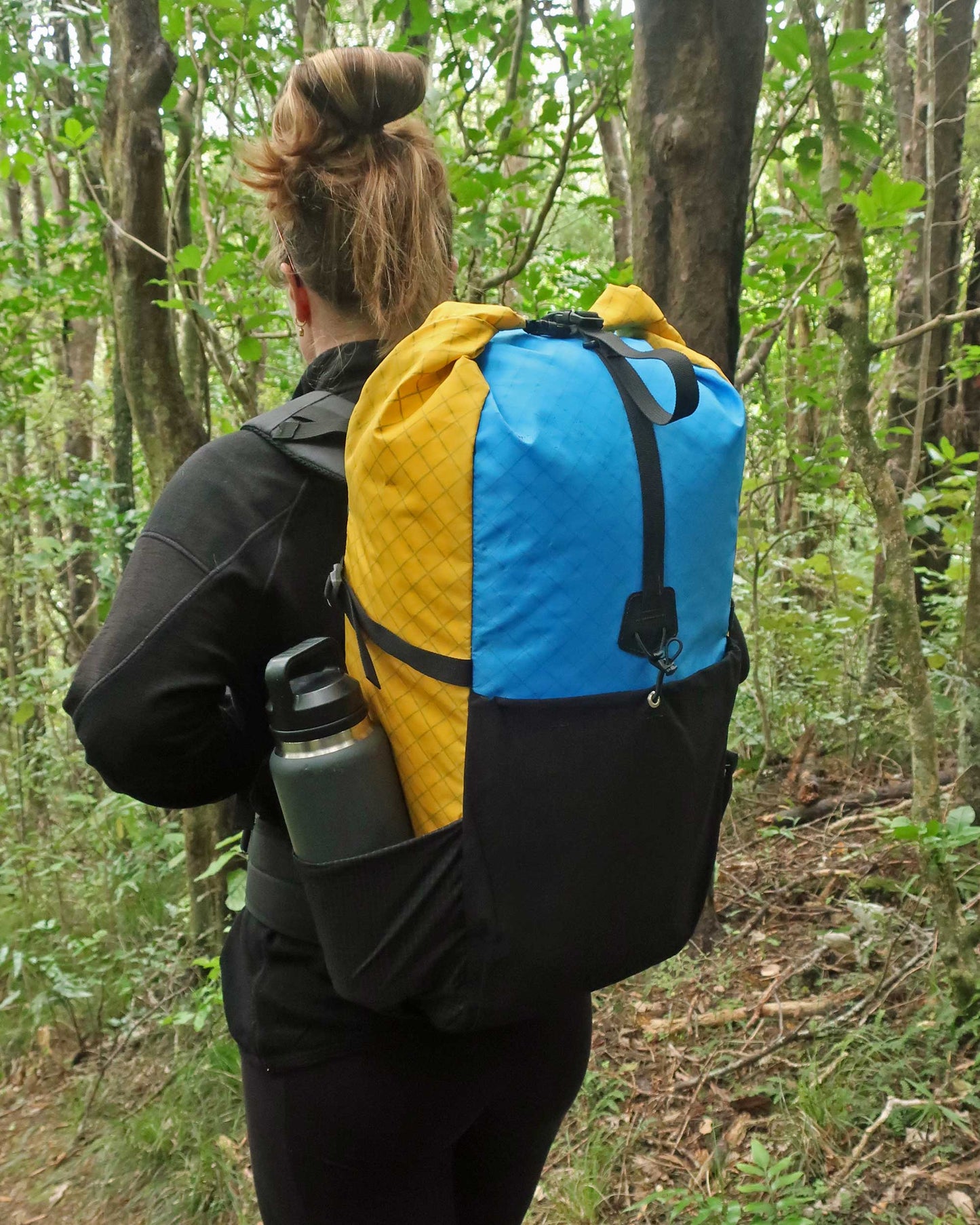 Multicolour Rata 40 hiking pack in NZ bush showing Ultragrid side pocket with water bottle, made by Stealth Wellington NZ