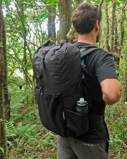 Rata 40 black overnight pack worn on NZ bush trail showing padded hip belt and Ultragrid side pocket, made by Stealth Wellington NZ
